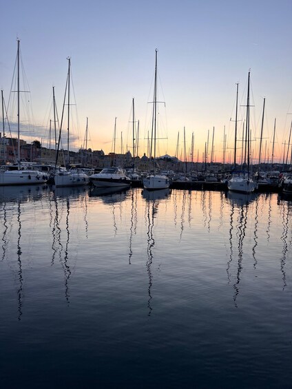 A marina with multiple sailboats docked at sunset. 3