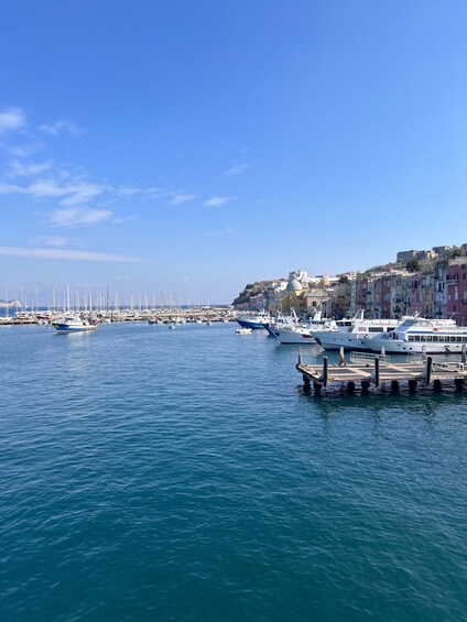 A harbor with boats docked, a pier, and buildings along the waterfront. 1