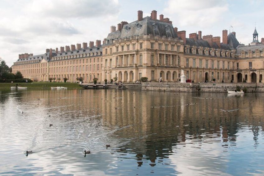 A large historic building with a reflective water body in front. 1