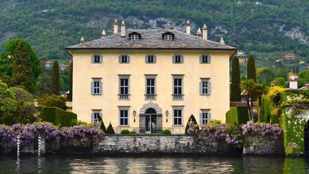 A large, yellow building with multiple windows and a central entrance, surrounded by water and greenery. 4