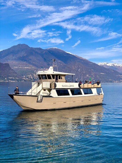 A boat named 'Bella Gioiosa Service' on calm water with a mountainous landscape in the background. 3