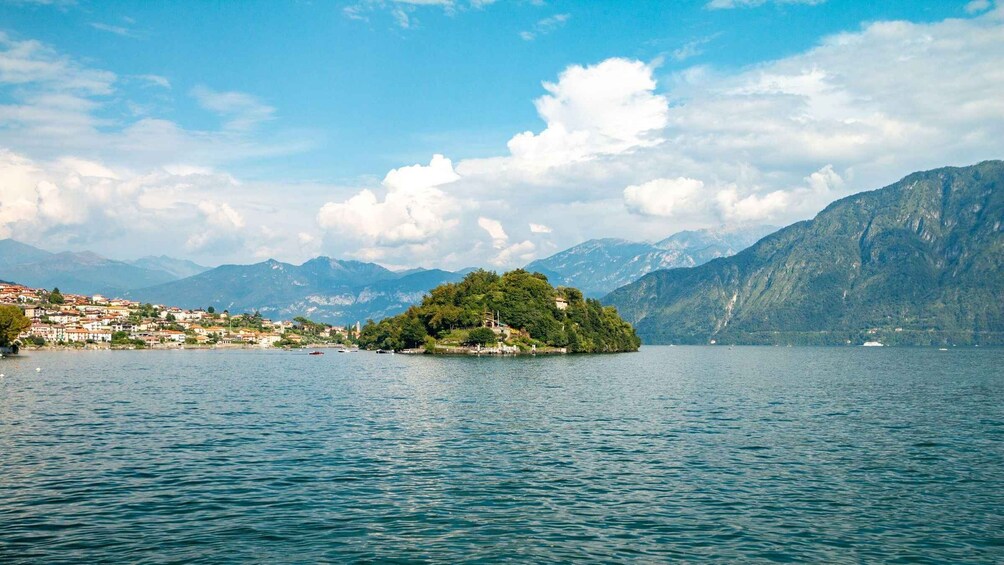 A lake with a small island, mountains in the background, and a town on the shore. 1