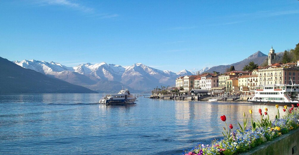 A lake with a boat, mountains in the background, and colorful flowers along the shore. 5