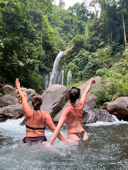 Two people in a natural setting with a waterfall and lush greenery. 5