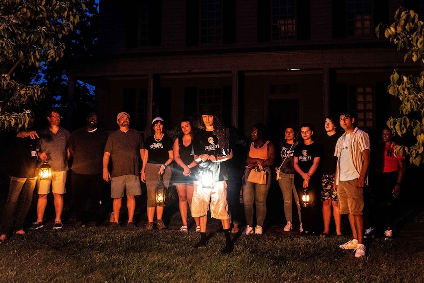 A group of people standing in front of a building at night with lanterns. 4