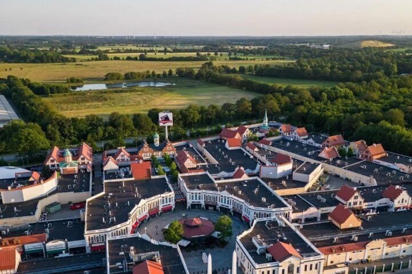 An aerial view of a town with red-roofed buildings, a church with a steeple, and a large flag on a flagpole. 2