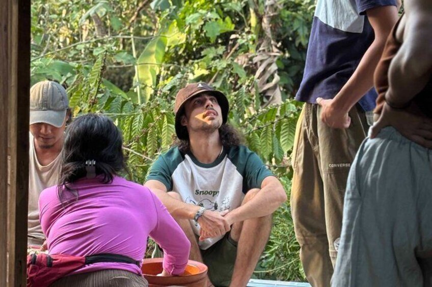 A group of people sitting outdoors, surrounded by greenery. 3
