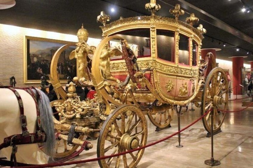 A golden carriage with intricate designs and a white horse. 4