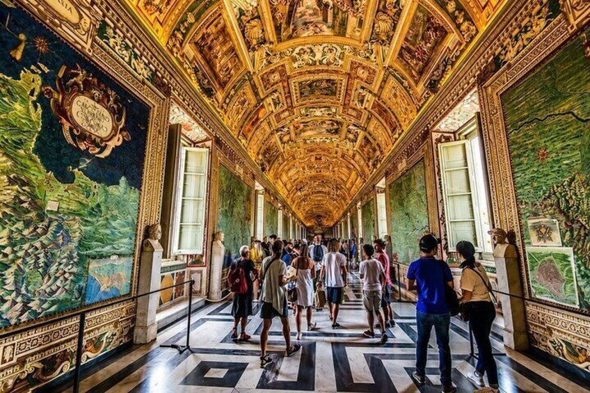 A long corridor with ornate ceiling and walls, lined with visitors. 3