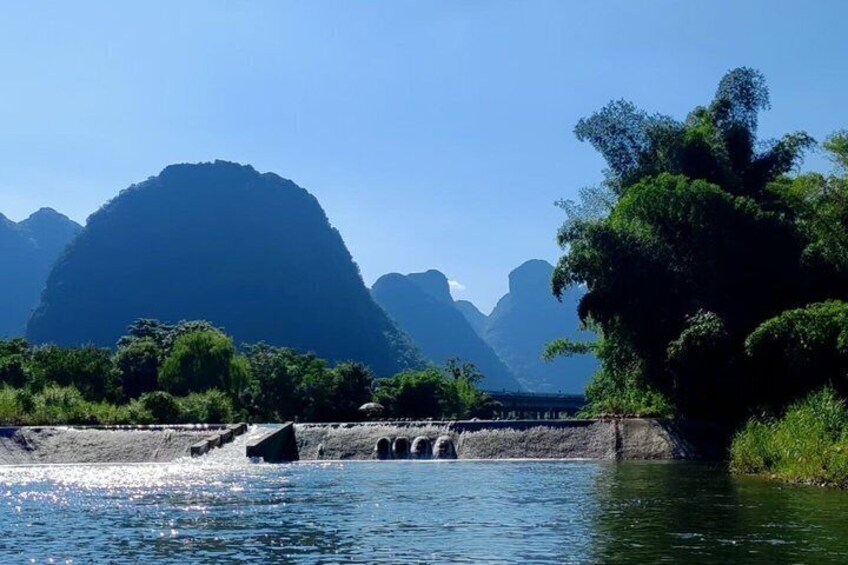 A river with a bridge, mountains, and greenery. 3