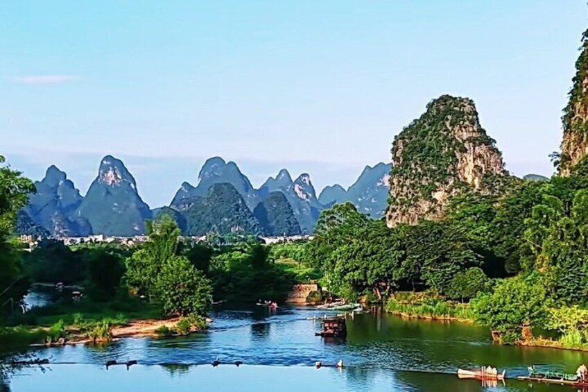 A river with boats, surrounded by lush greenery and karst limestone mountains. 5