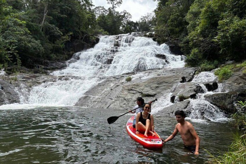 A waterfall, a person in a kayak, and another person standing in the water. 1