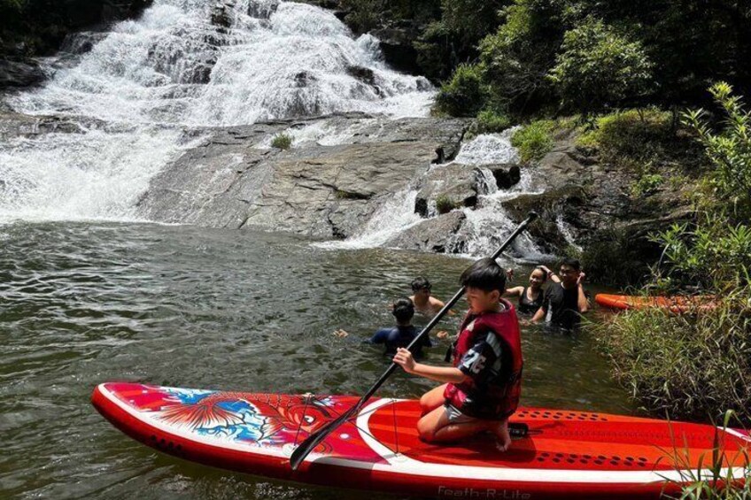 A person on a red paddleboard in a river with a waterfall in the background. 3