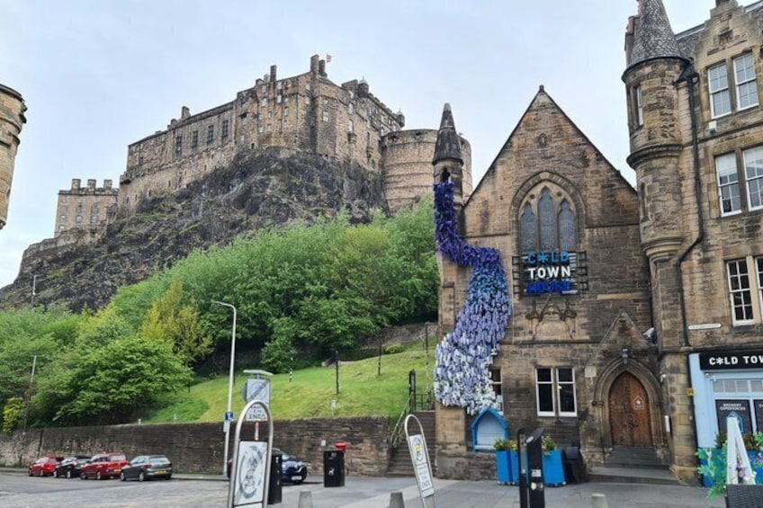A castle on a hill, a building with a sign reading 'Cold Town,' and a tall blue sculpture. 1