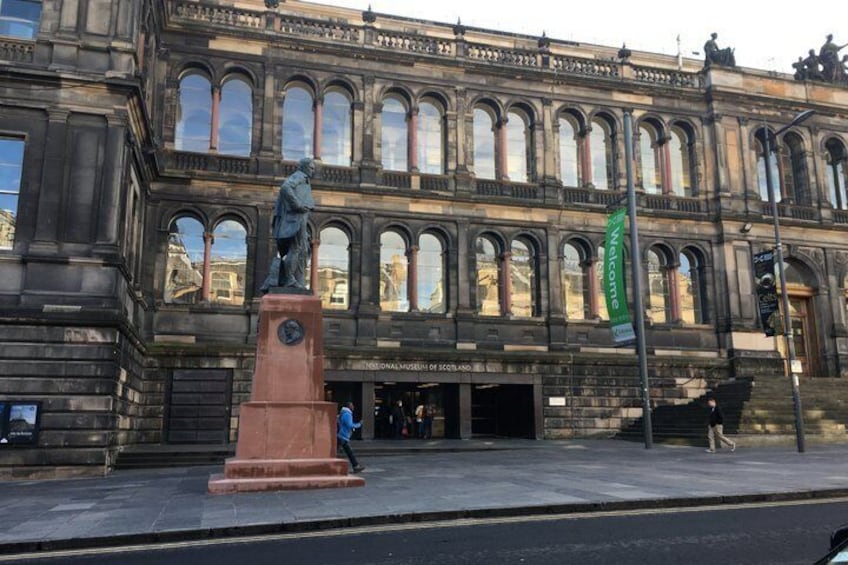 A historic building with arched windows and a statue in front. 4