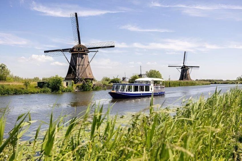 A river with two windmills and a boat. 5