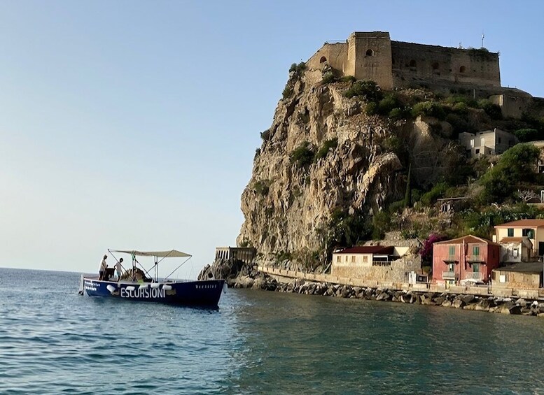 A coastal scene with a historic castle on a cliff, a boat with passengers, and a small town with buildings. 3