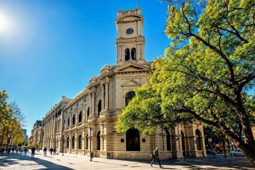 A historic building with a clock tower, surrounded by trees and a clear sky. 1