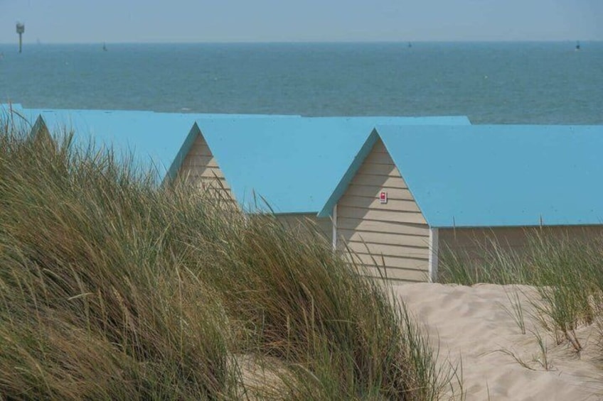 A beach with two wooden huts, sand dunes, and the ocean in the background. 5