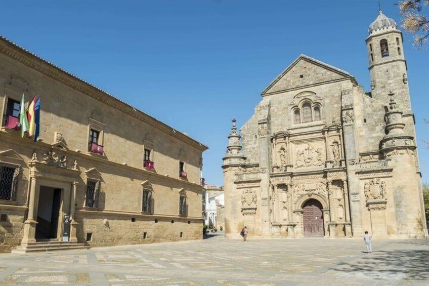 A historic building with a bell tower, a stone facade, and flags. 5