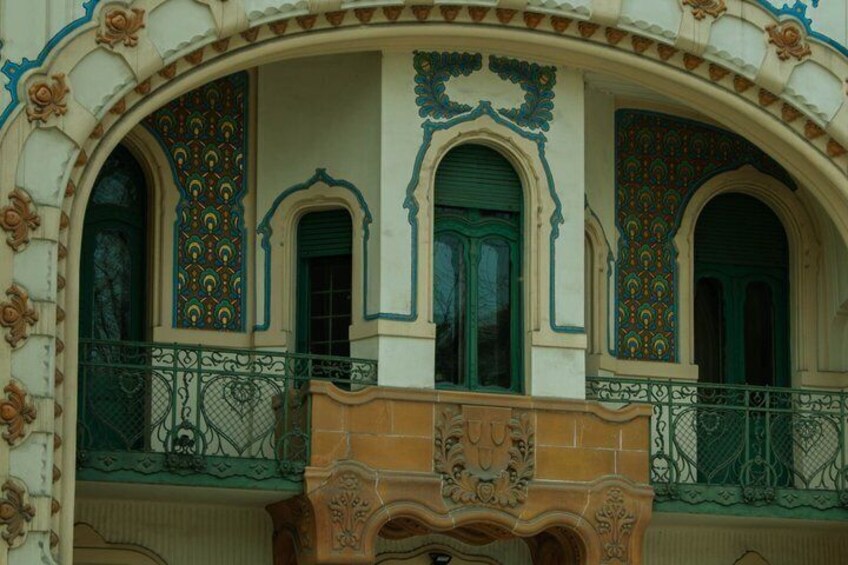 A building with ornate arches, green windows, and decorative patterns. 2