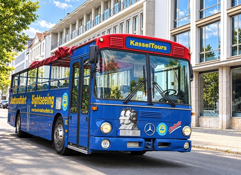 A blue sightseeing bus with 'KasselTours' and 'Sightseeing' written on it, parked on a street. 1