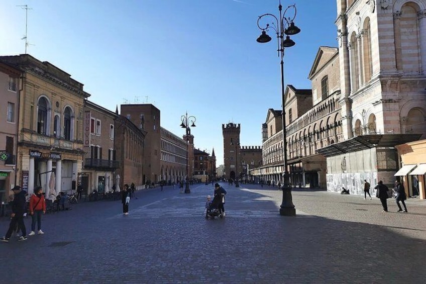 A cobblestone square with historic buildings, a tower, and a clear sky. 4