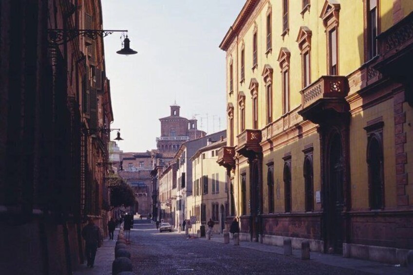 A cobblestone street lined with historic buildings, a clear sky, and a distant tower. 3