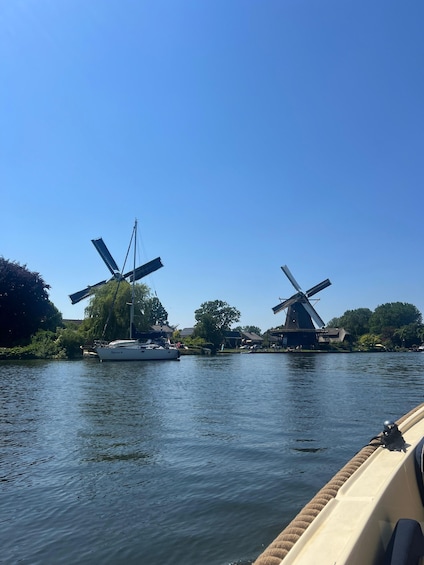 A river with two windmills and a sailboat. 5