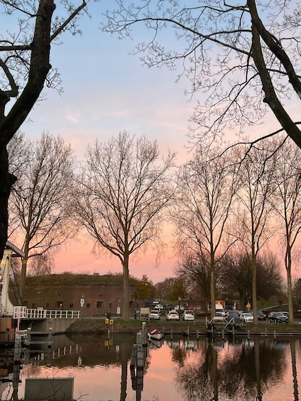 A riverside scene with trees, a dock, and parked cars. 2