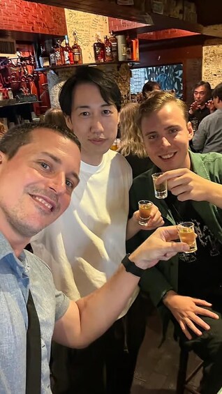 Three people in a bar with bottles and glasses. 3