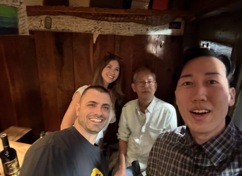 A group of people in a wooden room with a bottle on the table. 5