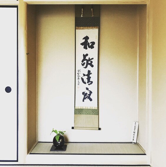 A traditional Japanese scroll with calligraphy, a small potted plant, and a framed piece of paper. 5