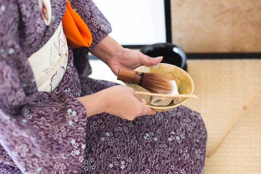 A person holding a bowl with a whisk and a cloth. 1