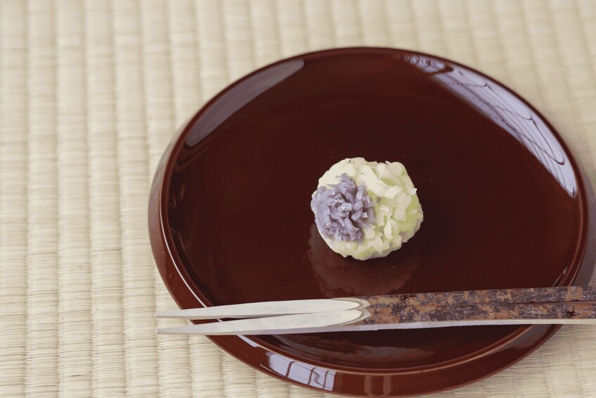 A plate with a brown sauce and a white and purple food item, accompanied by a pair of chopsticks. 3