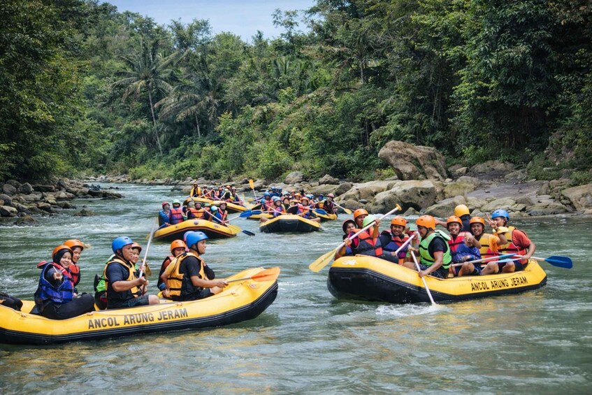Eine Gruppe von Menschen treibt auf einem Fluss, umgeben von dichtem Grün. 3