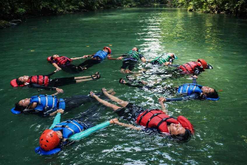 Eine Gruppe Menschen treibt in Schwimmwesten einen Fluss hinab. 5