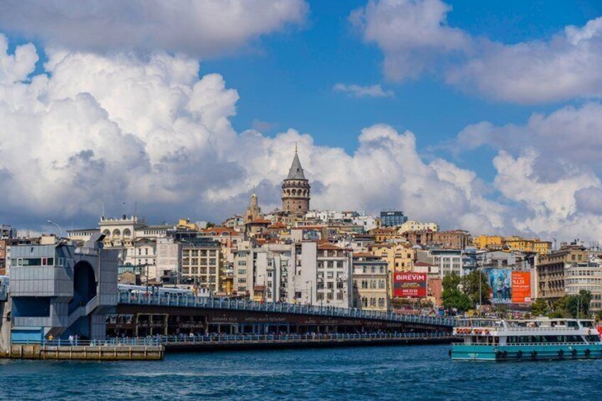 A coastal cityscape with a prominent tower, a bridge, and a ferry. 1