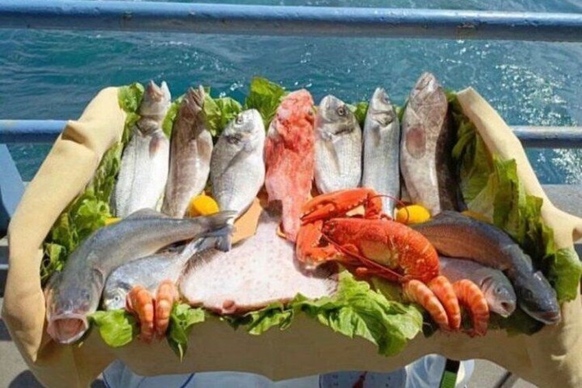 A variety of seafood including fish, lobster, and shrimp, arranged on a table with lettuce and lemon slices. 5