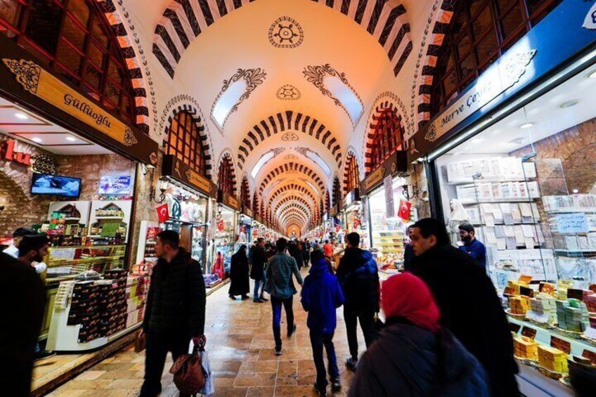 A bustling indoor market with a high, arched ceiling and various shops on either side. 4