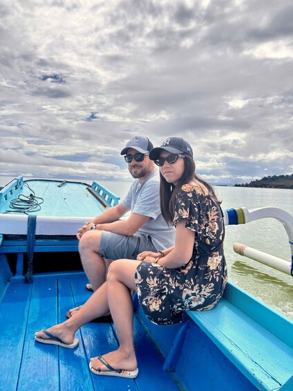 Two people sitting on a blue boat with a cloudy sky in the background. 3