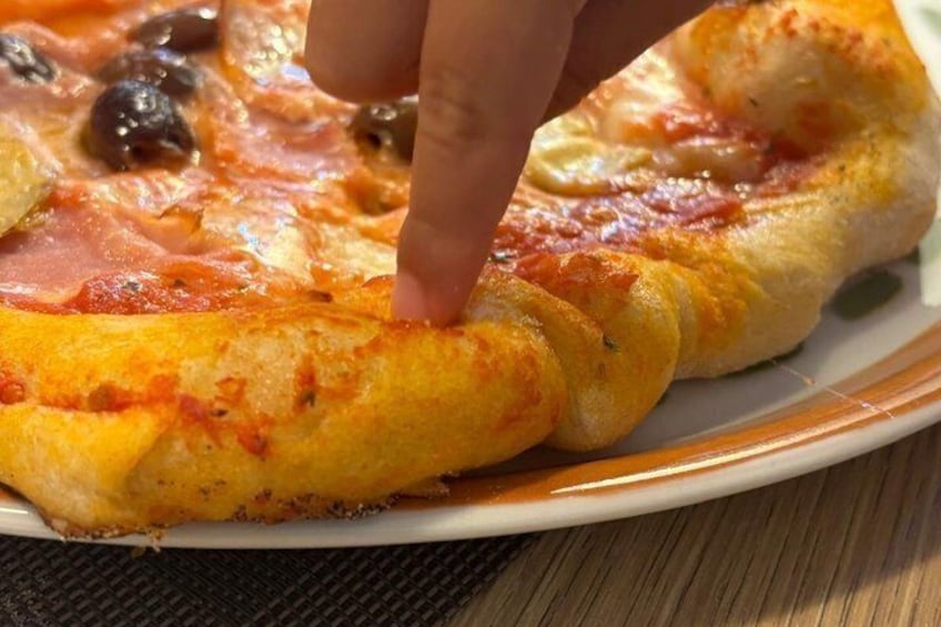 A slice of pizza with a hand touching it. 5