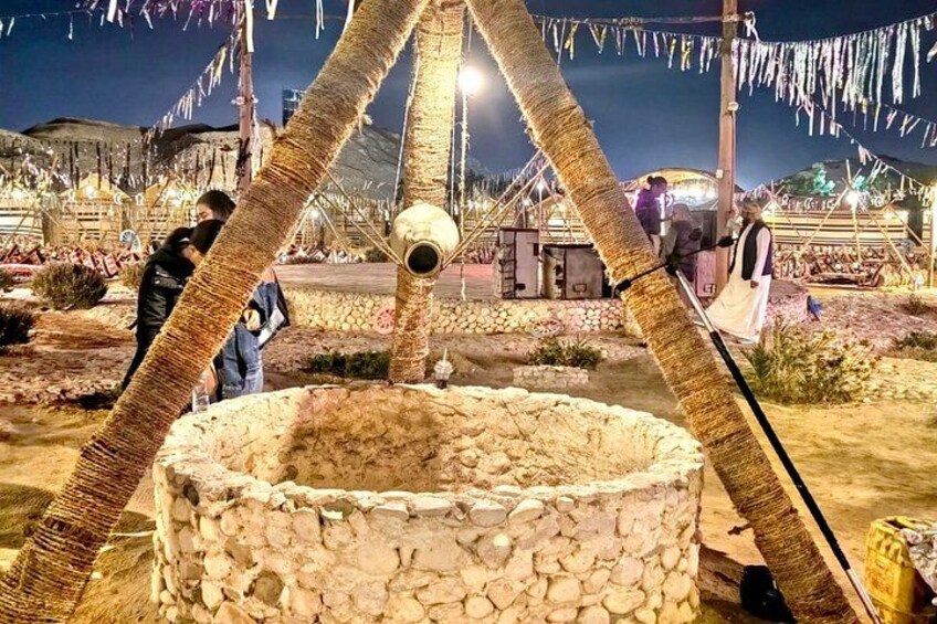 A stone well with a spherical object inside, surrounded by decorative ropes and a festive atmosphere. 3