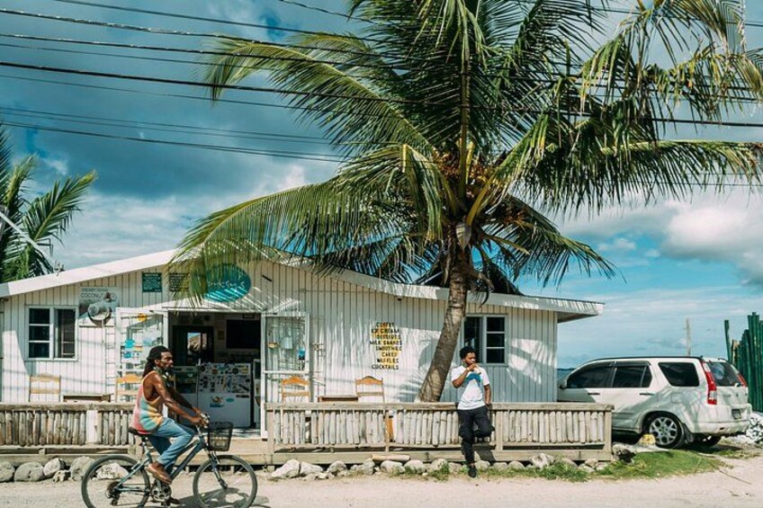 A small building with a signboard, a bicycle, and a person standing by a car. 5