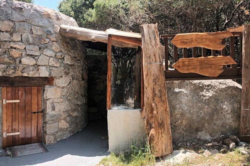 A stone building with a wooden door, a wooden archway, and a wooden sign. 2