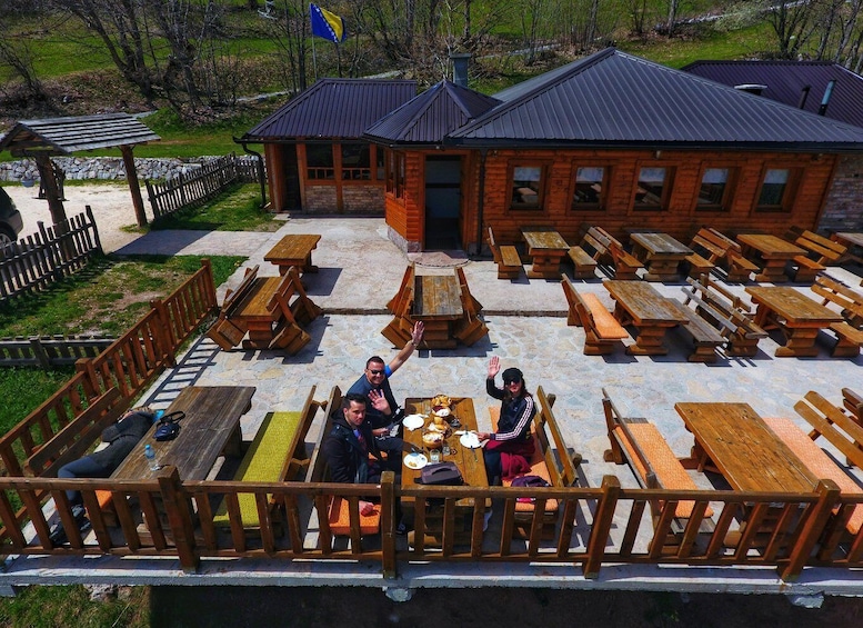 A wooden deck with picnic tables, a brick building, and a flag. 5