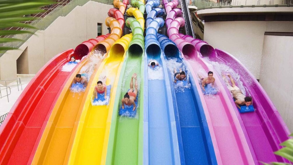 A multi-colored water slide with people sliding down. 1
