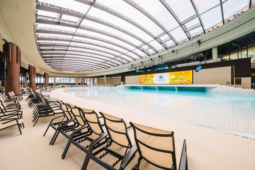 A large indoor swimming pool with a curved ceiling and rows of chairs. 3