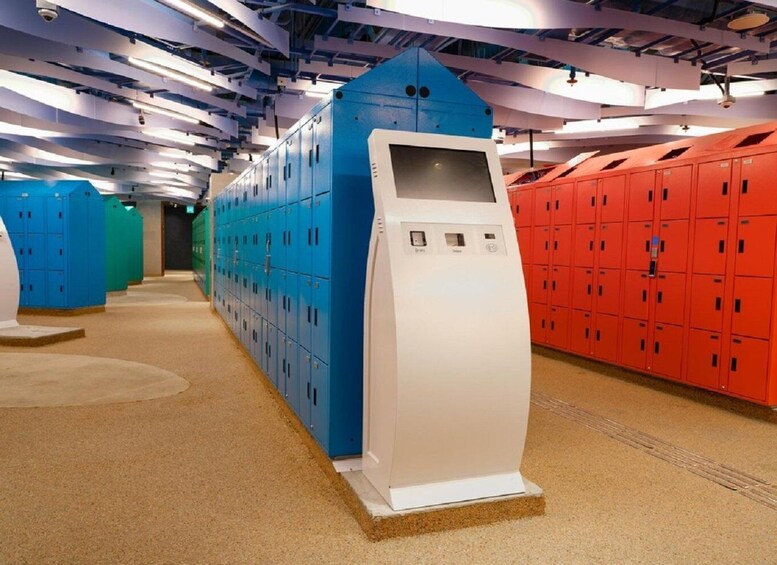 A locker room with rows of lockers in blue, green, and red colors, and a white security kiosk. 4
