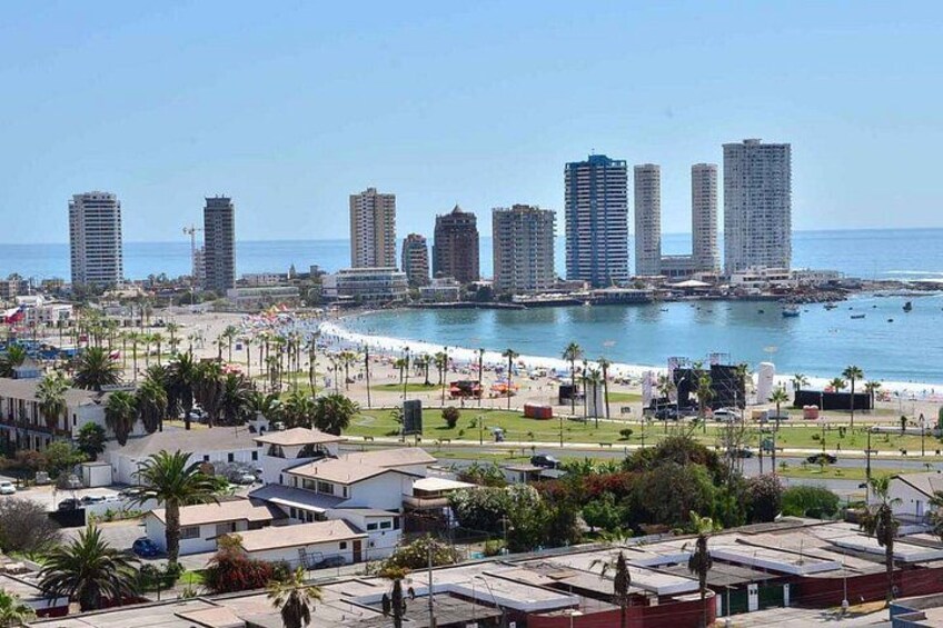 A coastal cityscape with high-rise buildings, a beach, and a marina. 2